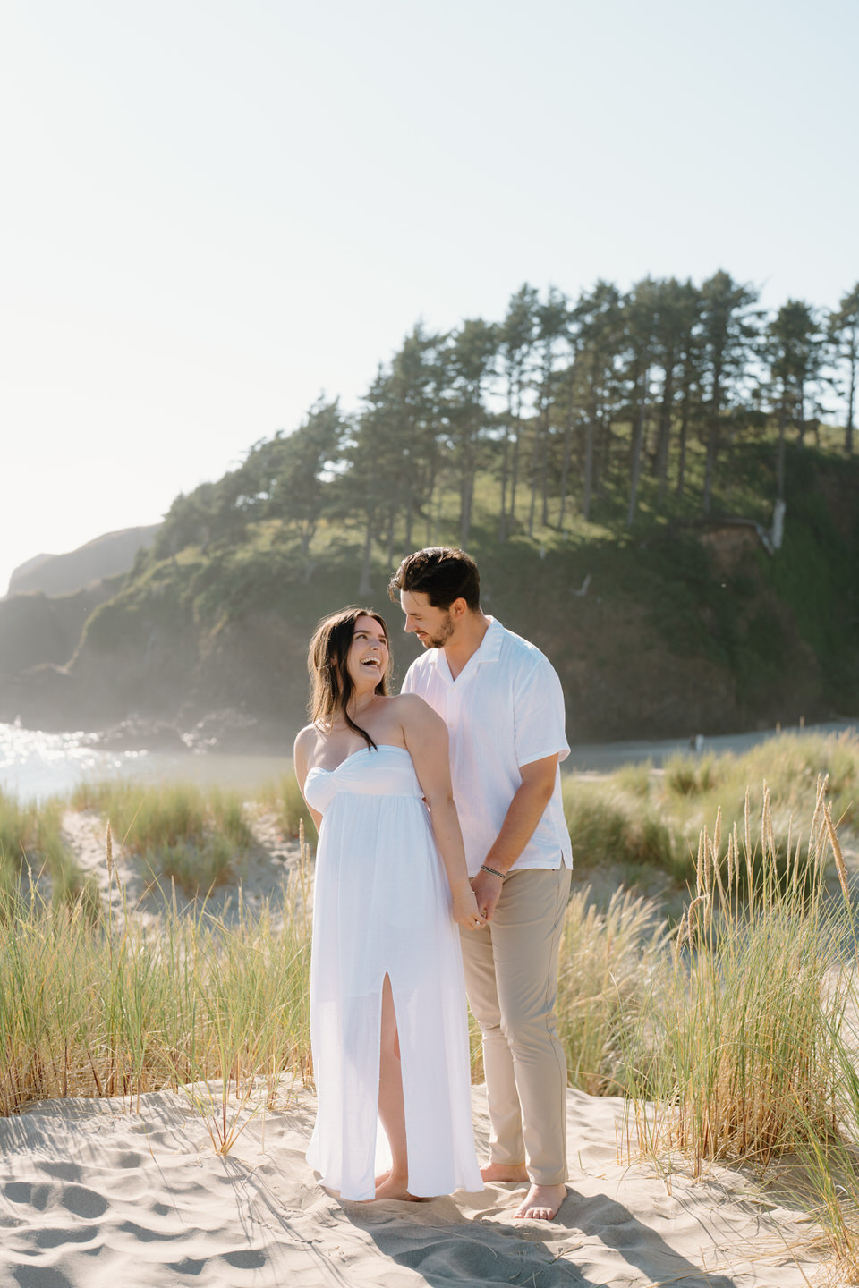 Couple holds hands on top of the grassy hills on the Oregon coast. 