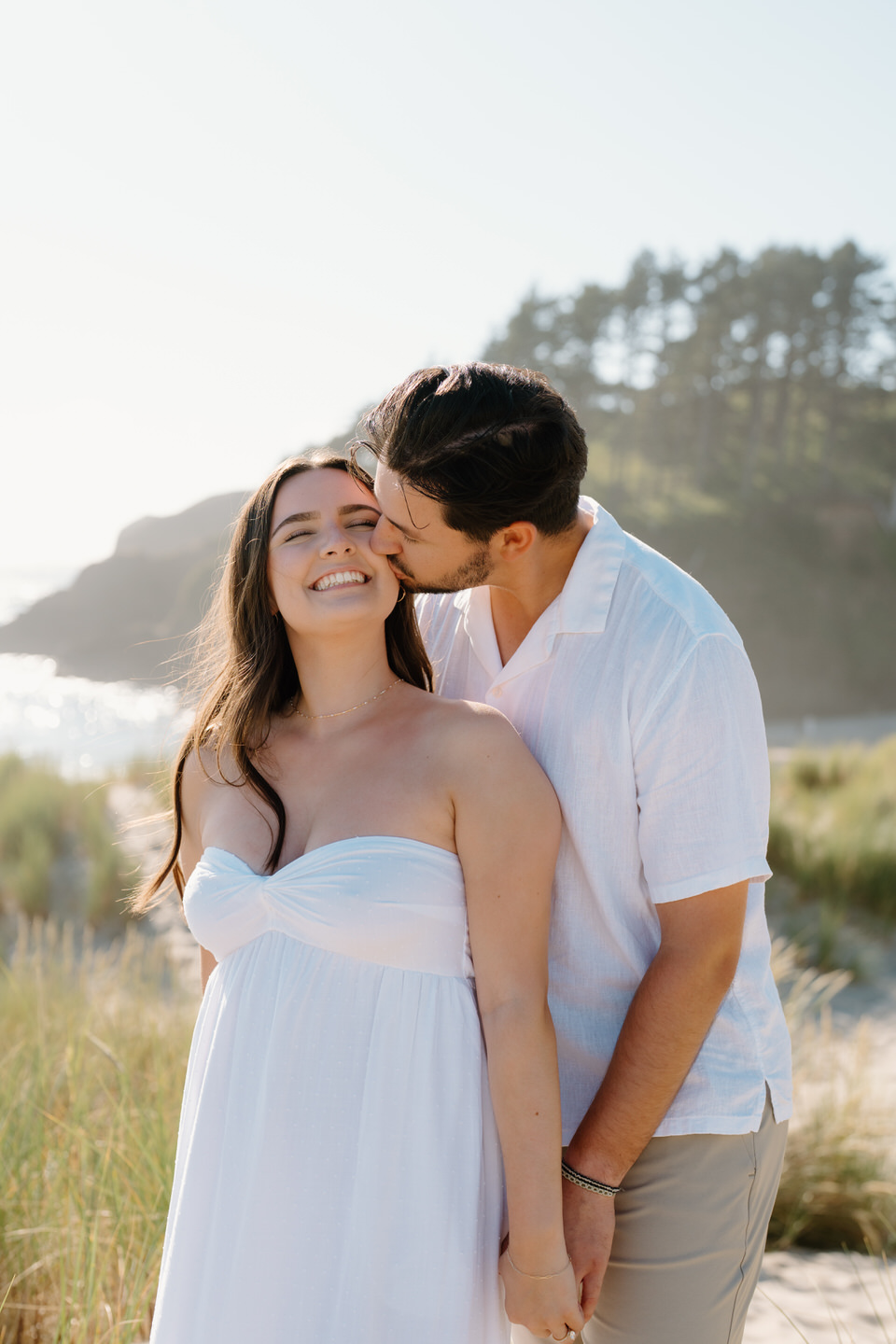 Man kisses woman on the cheek for their engagement shoot.