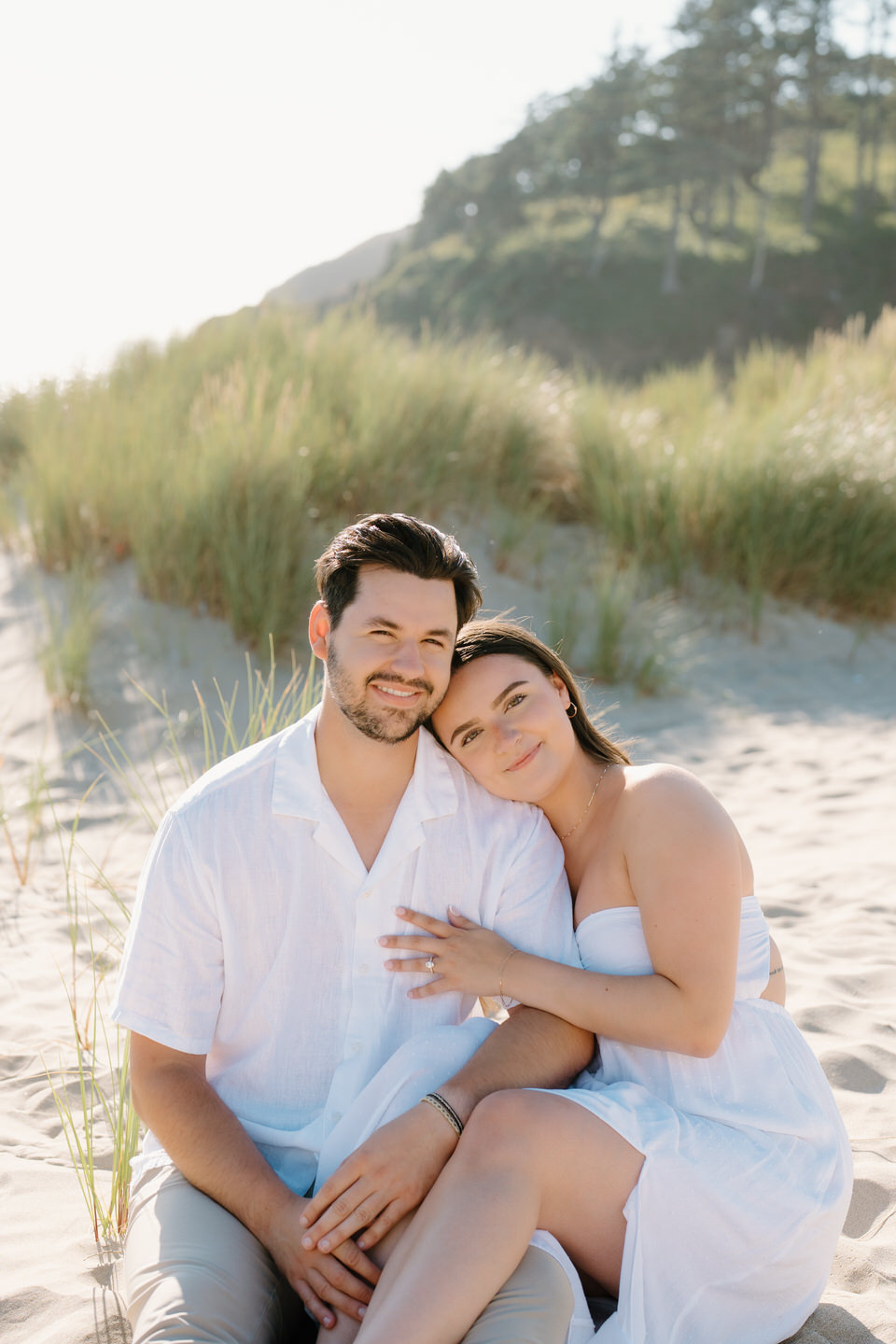 Couple seated in the grassy hills near Cannon Beach, Oregon.