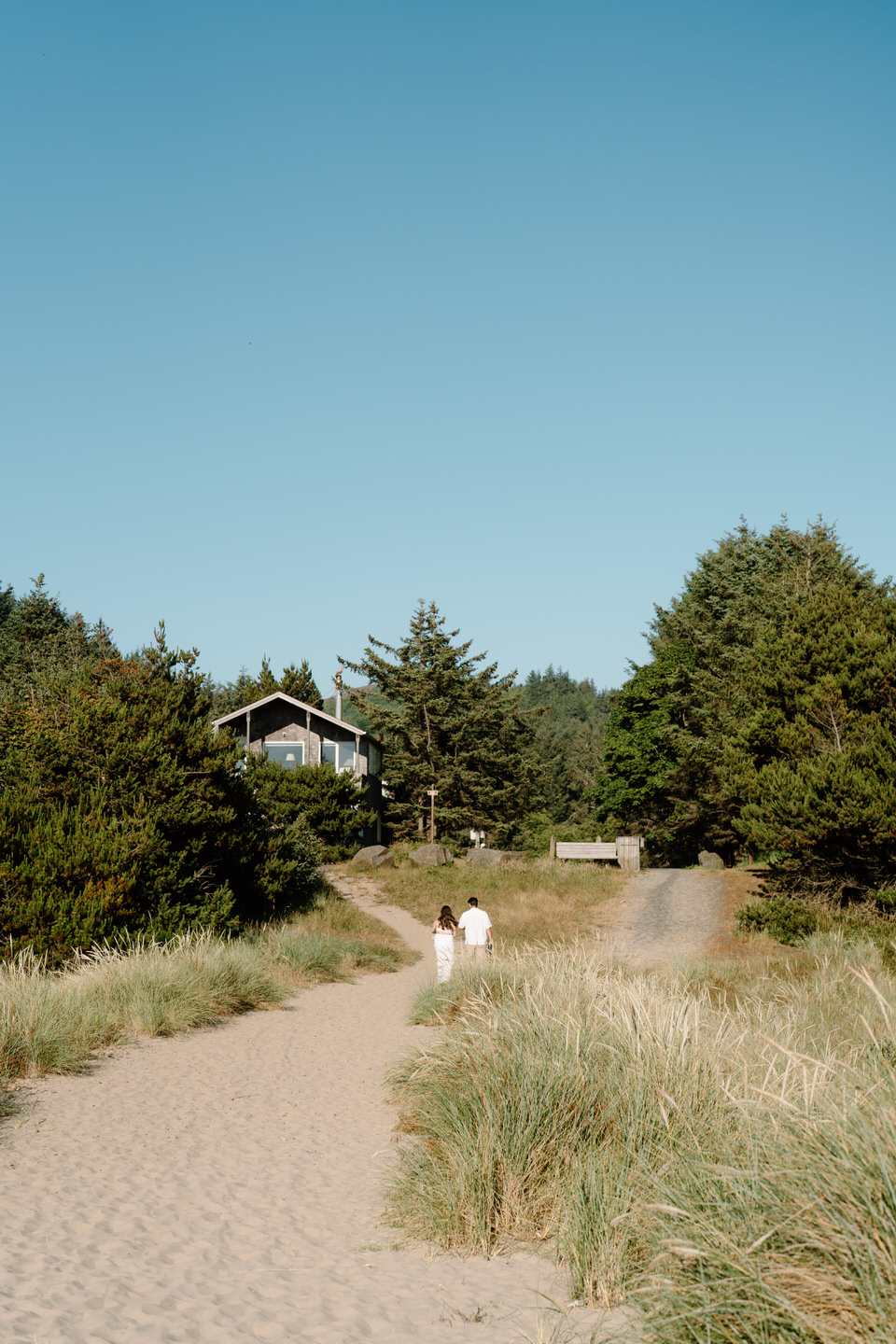 Candid photo of couple walking back to their car on the Oregon coast beach path.
