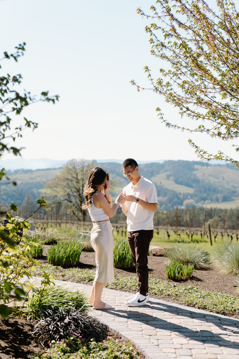 Emotional proposal moment at Eminent Domaine winery with spring greenery and mountain views in the background.