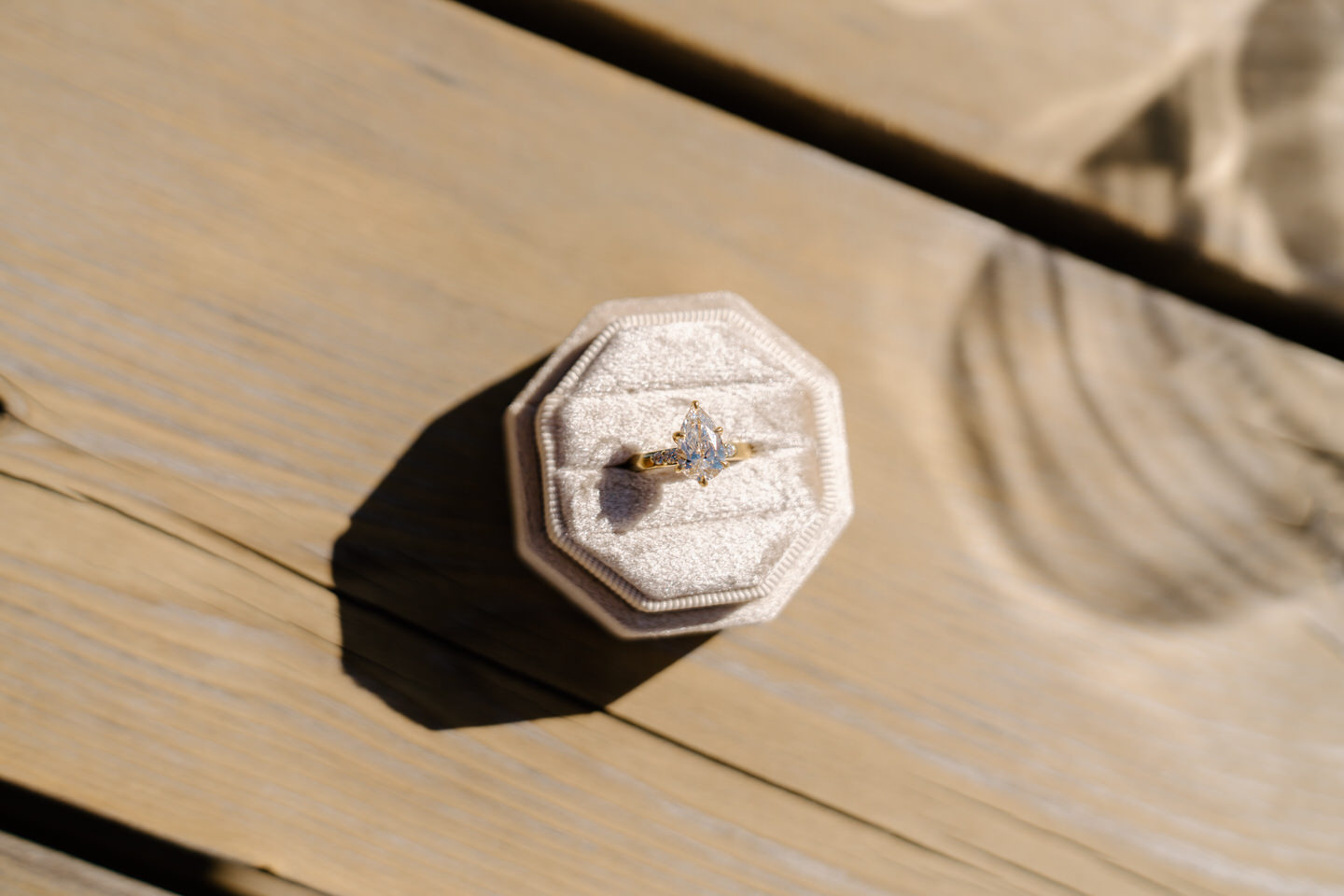 Pear shaped engagement ring photographed on a wooden table at Eminent Domaine winery during an April vineyard proposal.