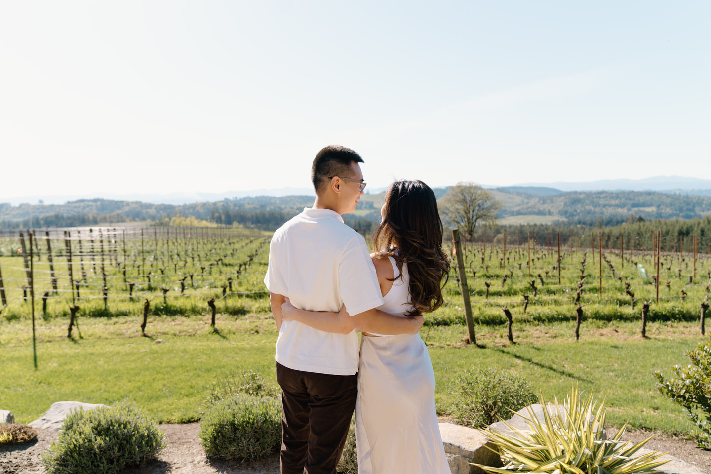 Oregon wine country proposal at Eminent Domaine winery with couple holding wine glasses and celebrating their engagement.