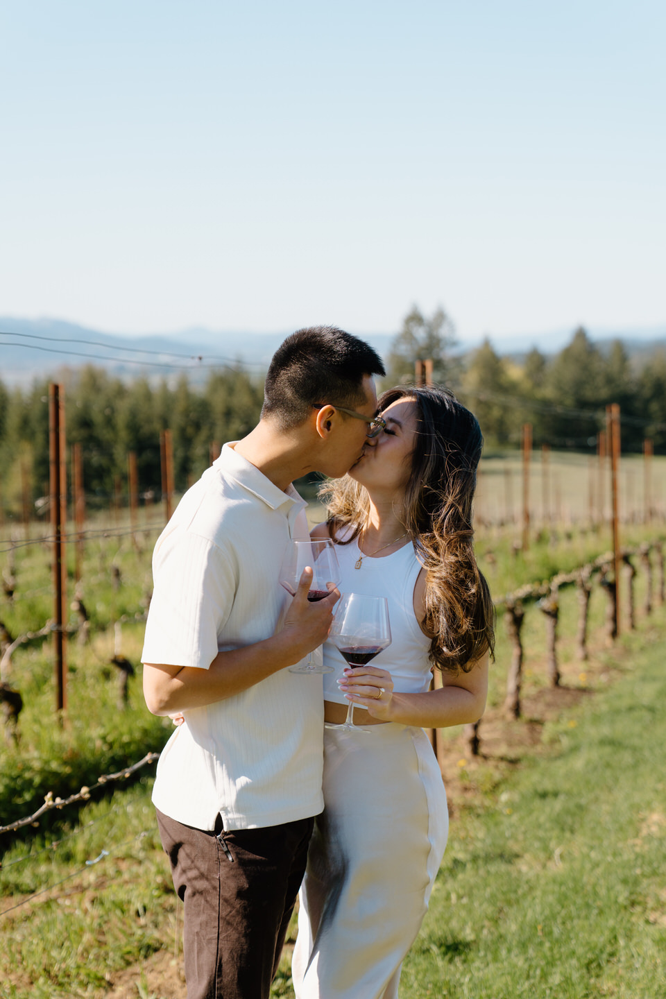 Oregon wine country proposal featuring couple kissing between vineyard rows at Eminent Domaine winery in early spring.