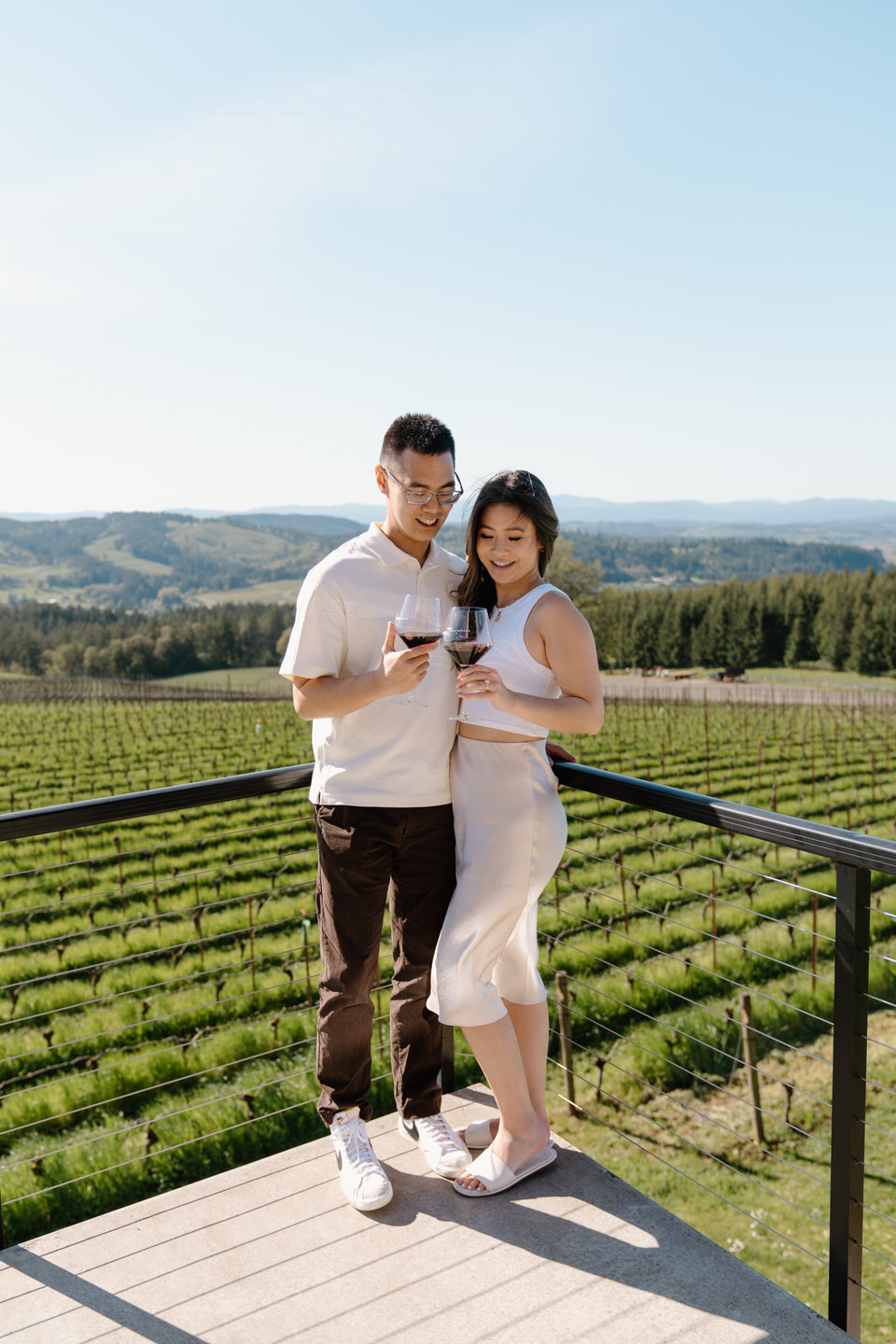 Oregon wine country proposal scene with couple standing on terrace at Eminent Domaine winery in April sunshine.