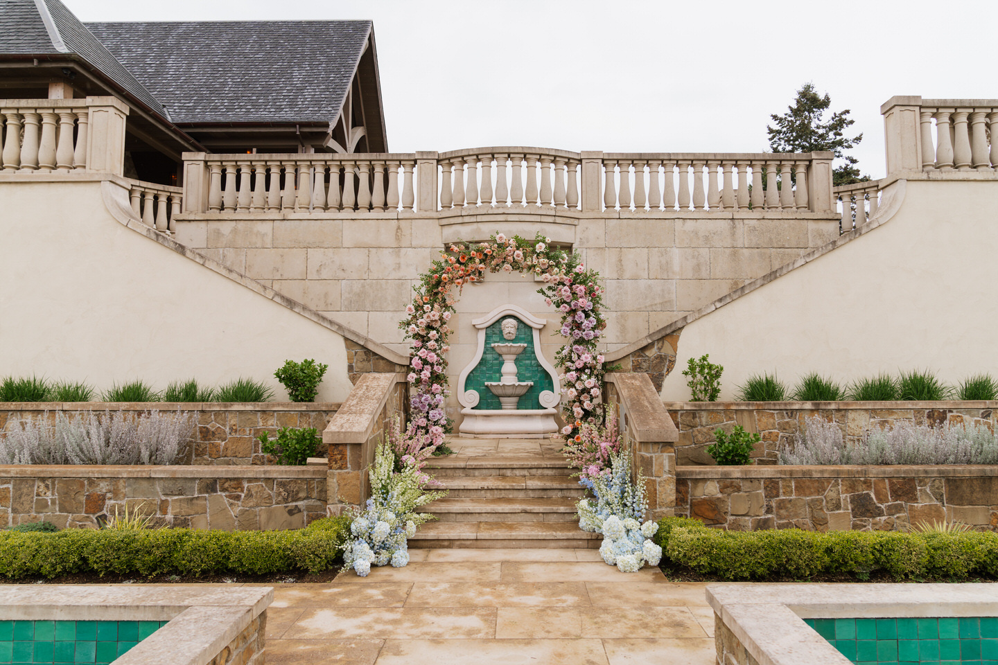 Ceremony aisle framed by florals at Chateau de Lis with stone steps and European garden elegance.