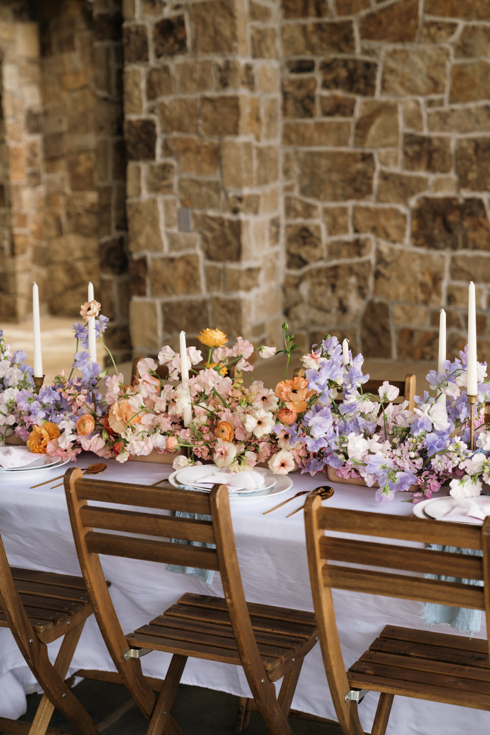 Elegant reception table at Chateau de Lis layered with bright florals, linens, and refined place settings.