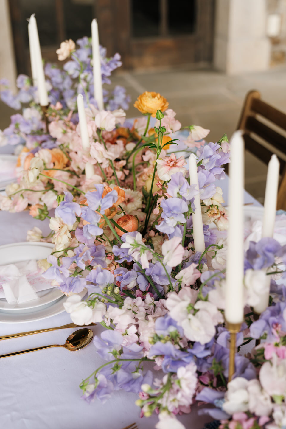 Floral centerpiece with pastel blooms and taper candles at Chateau de Lis styled for a luxury spring wedding.