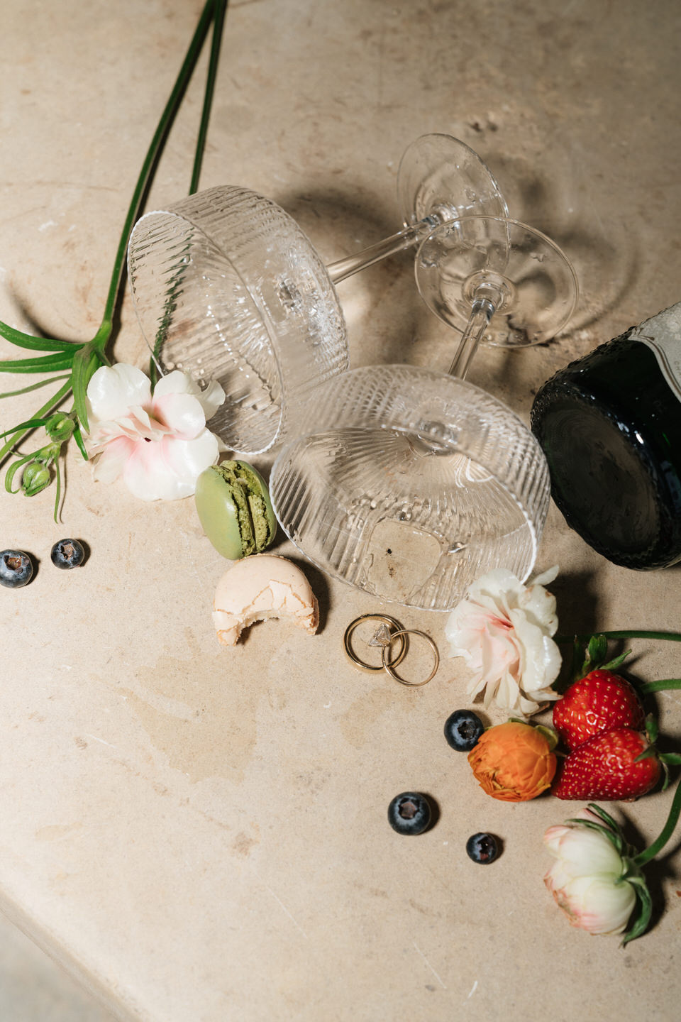 Luxury late-night flat lay with rings, florals, and fruit details styled for a spring wedding editorial.