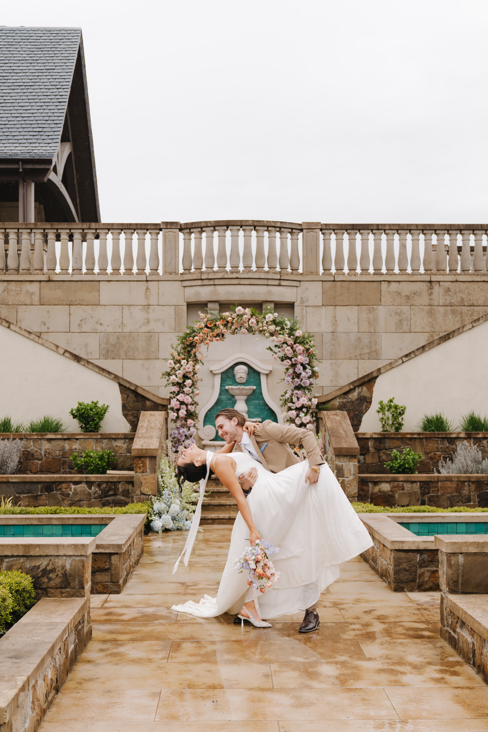 Bride twirls playfully in front of a floral arch, her dress flowing in the open courtyard at chateau de lis.