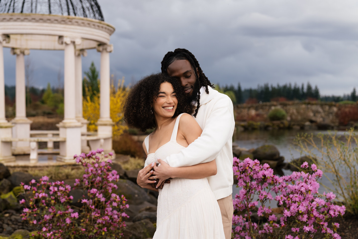Romantic portrait of couple embracing near the pond with trees and reflections creating a serene backdrop.