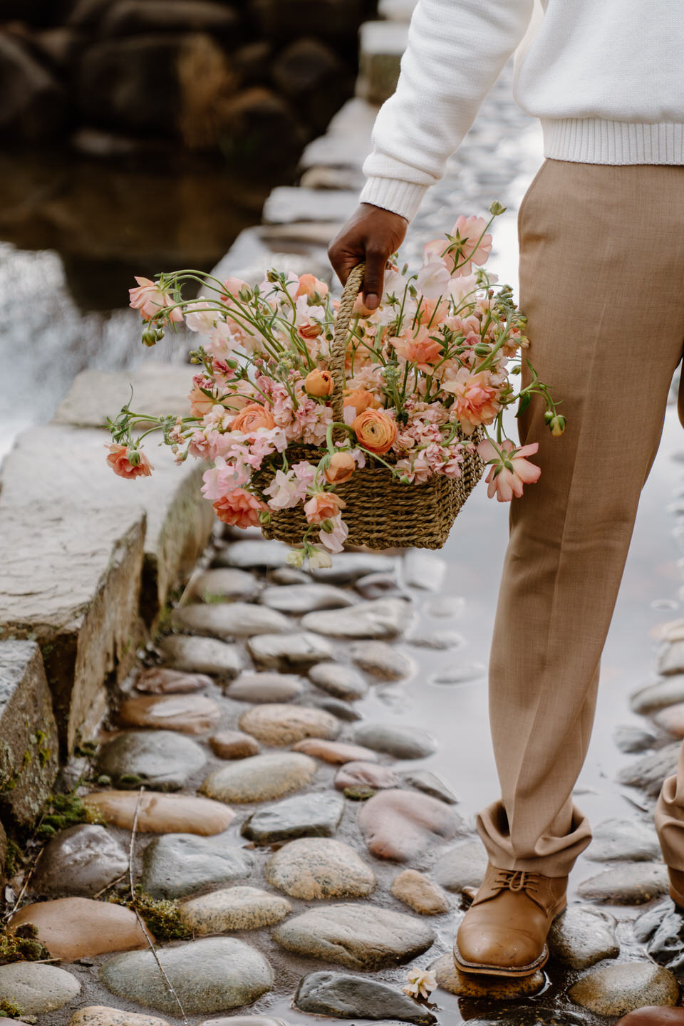Close up of pink and orange flower arrangement in a wicker basket.