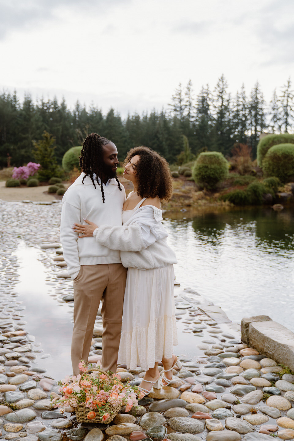 Cozy embrace at Chateau de Lis near the pond, surrounded by evergreens and peaceful garden scenery.