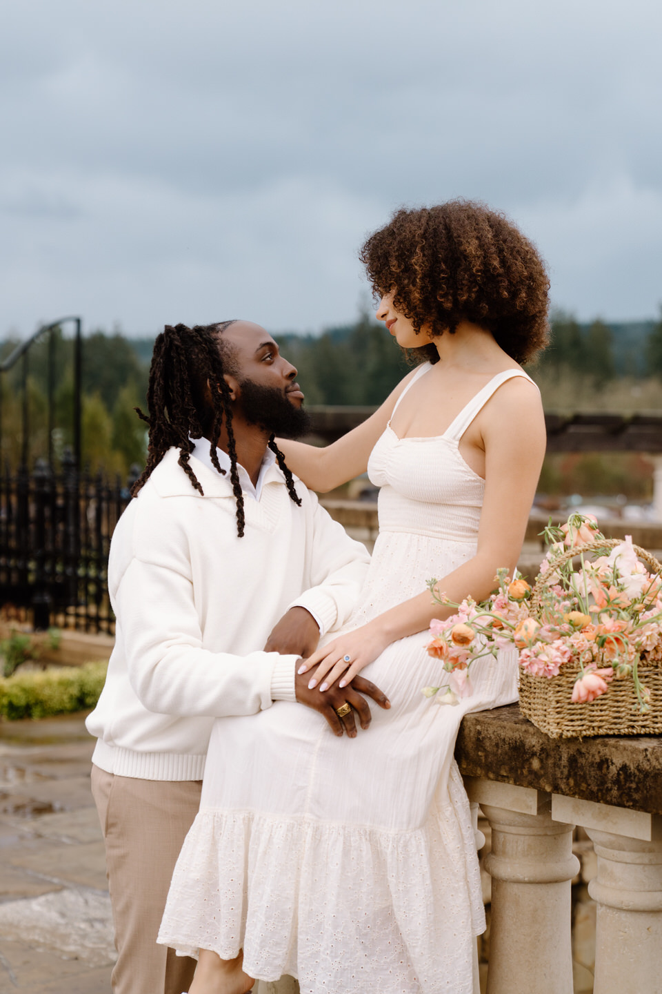 Couple seated together with bouquet at Chateau de Lis, sharing a quiet romantic moment by the garden edge.