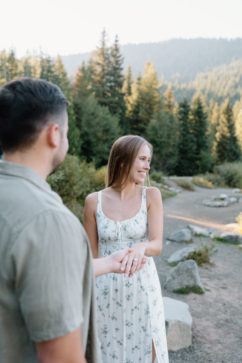 Fiancé looking lovingly at his partner as she laughs during engagement photos at Trillium Lake forest edge.