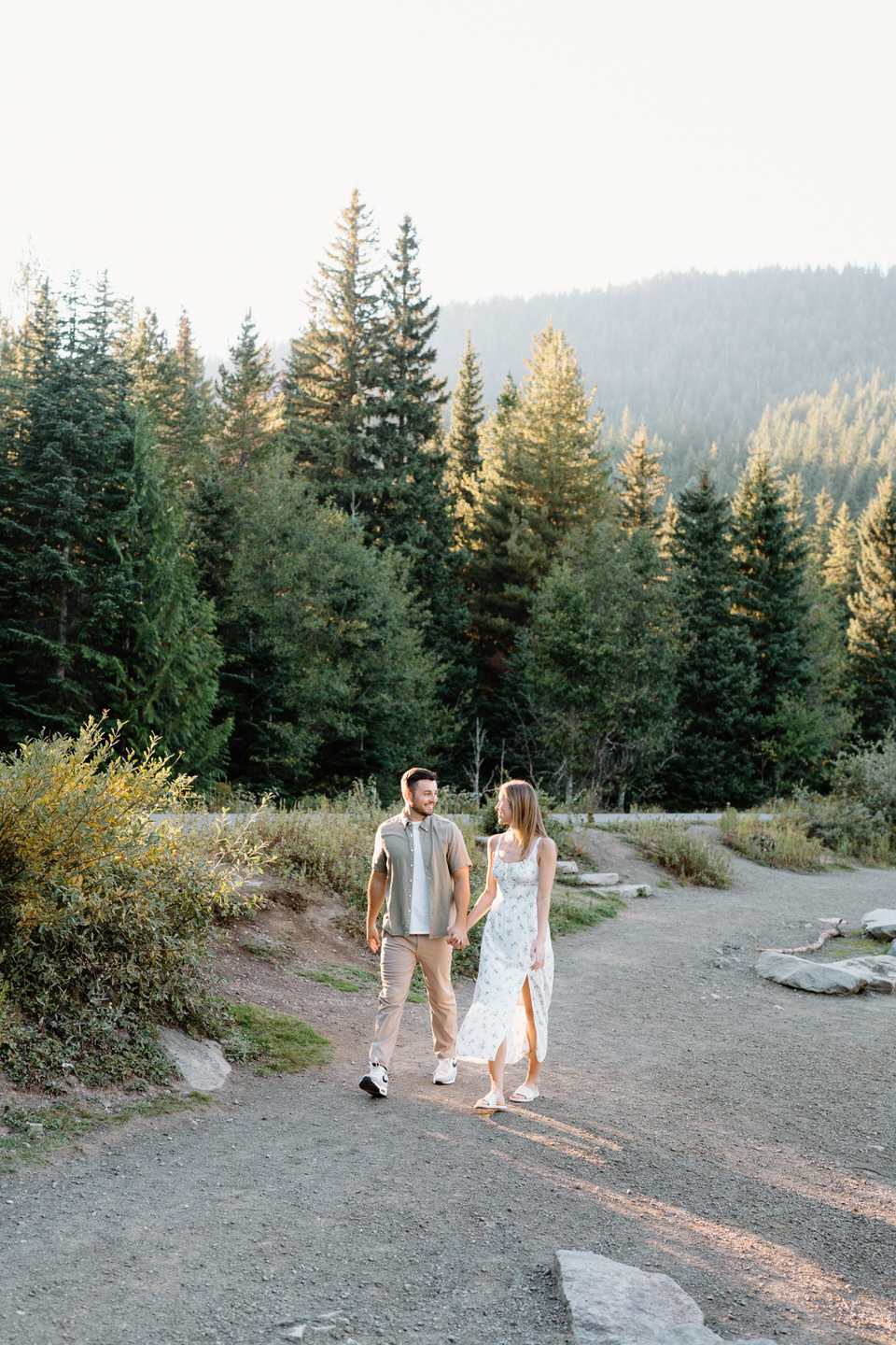 Engaged couple walks along the gravel shore at Trillium Lake for their engagement photos.