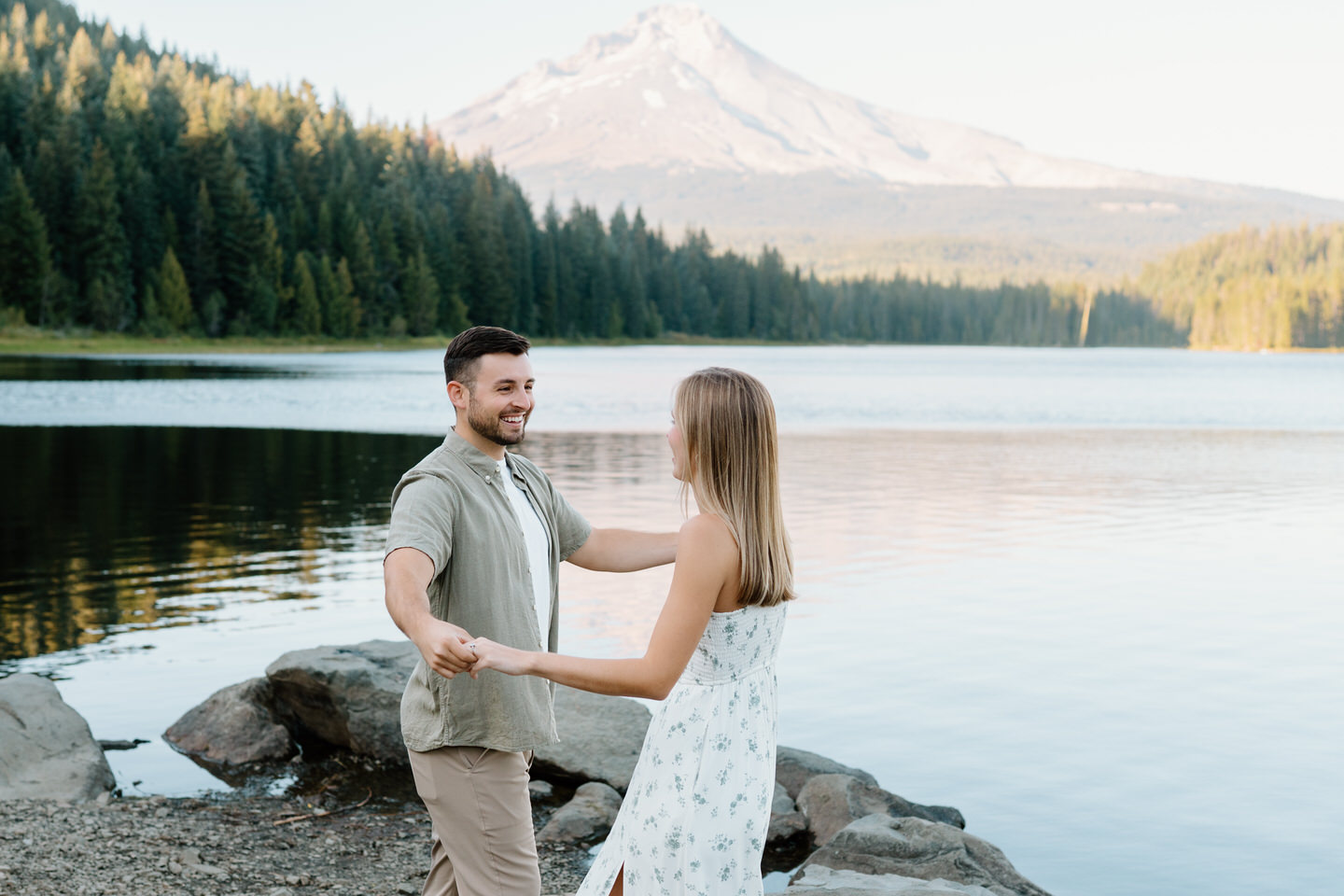 Fiancé spins his partner playfully near the lakeshore during engagement photos at Trillium Lake in September.