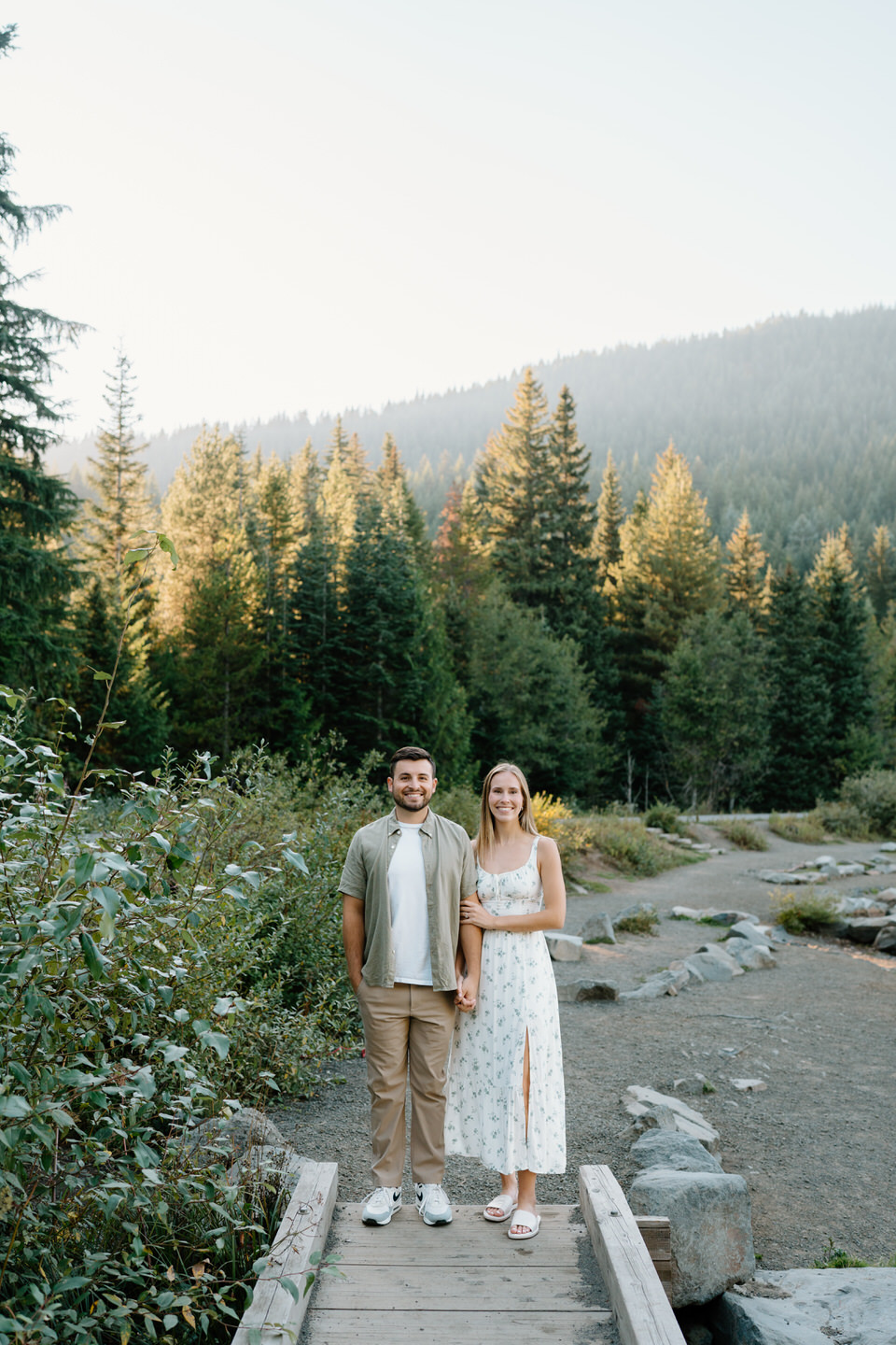 Couple walking hand in hand down a forest trail surrounded by evergreens near Trillium Lake in early fall.