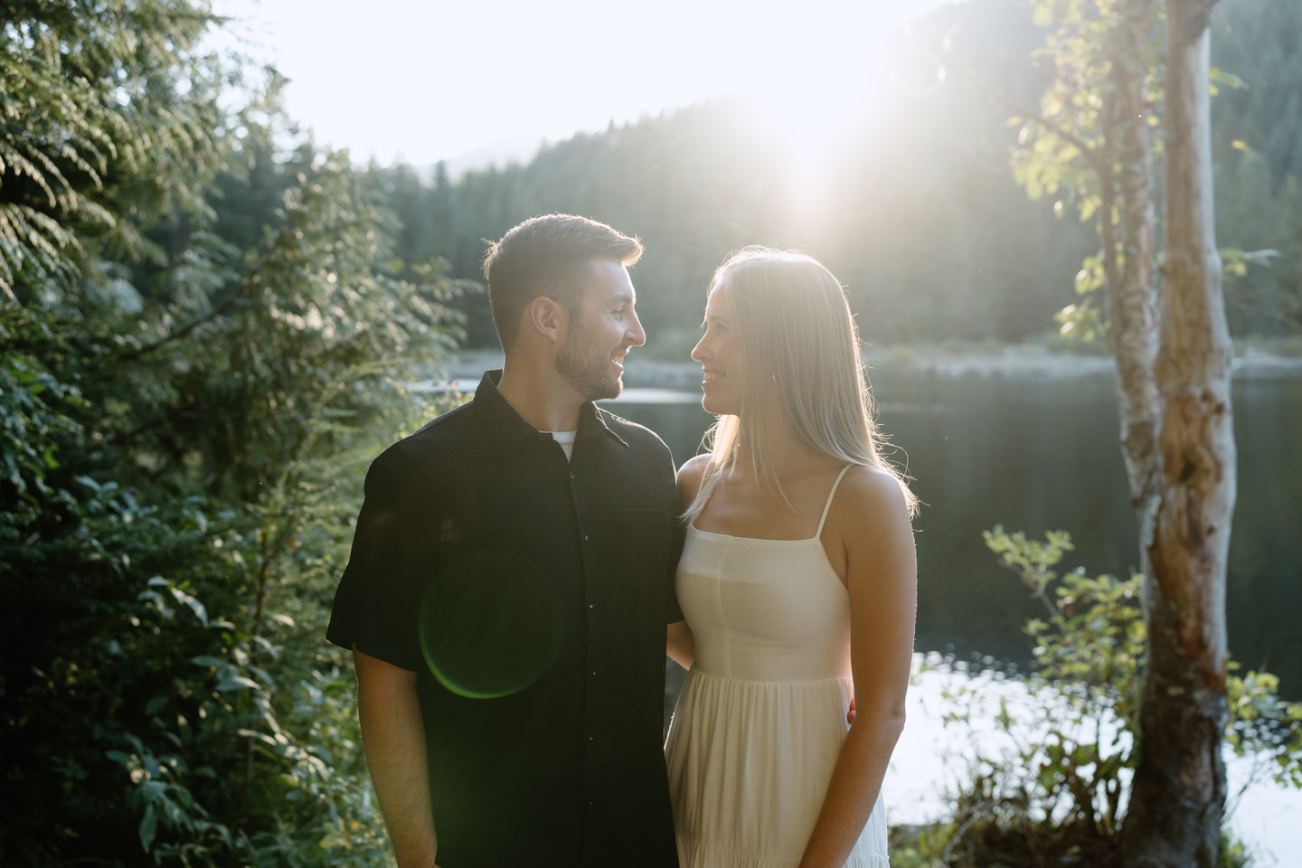 Sun flare shines behind the couple as they look at each other during engagement photos at Trillium Lake in September.
