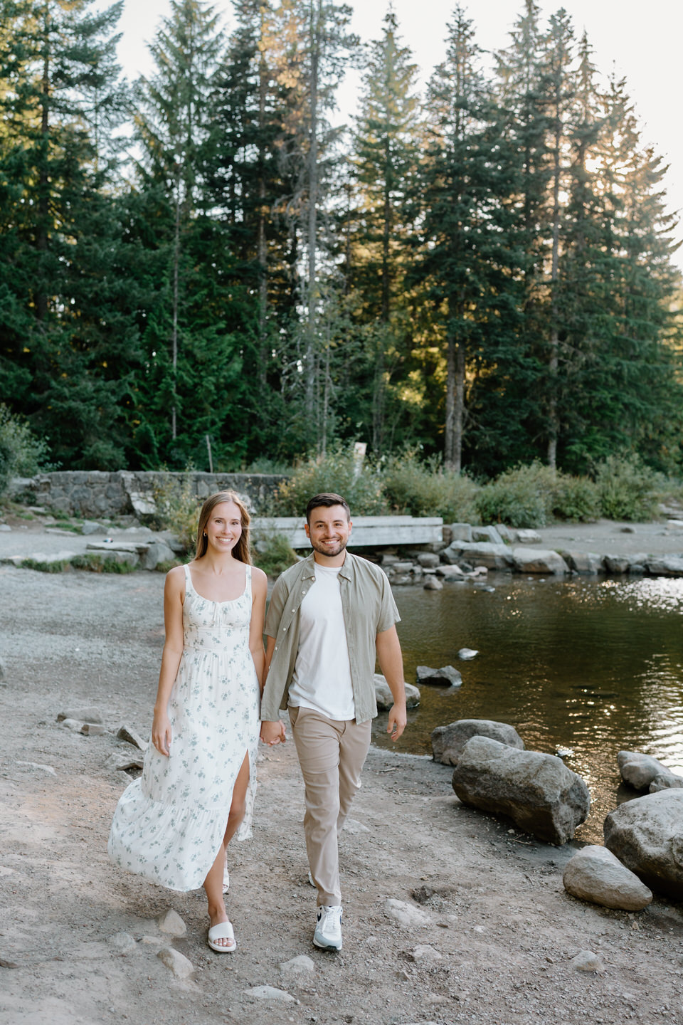 Couple smiling at each other while walking through the forest after outfit change during engagement photos at Trillium Lake.