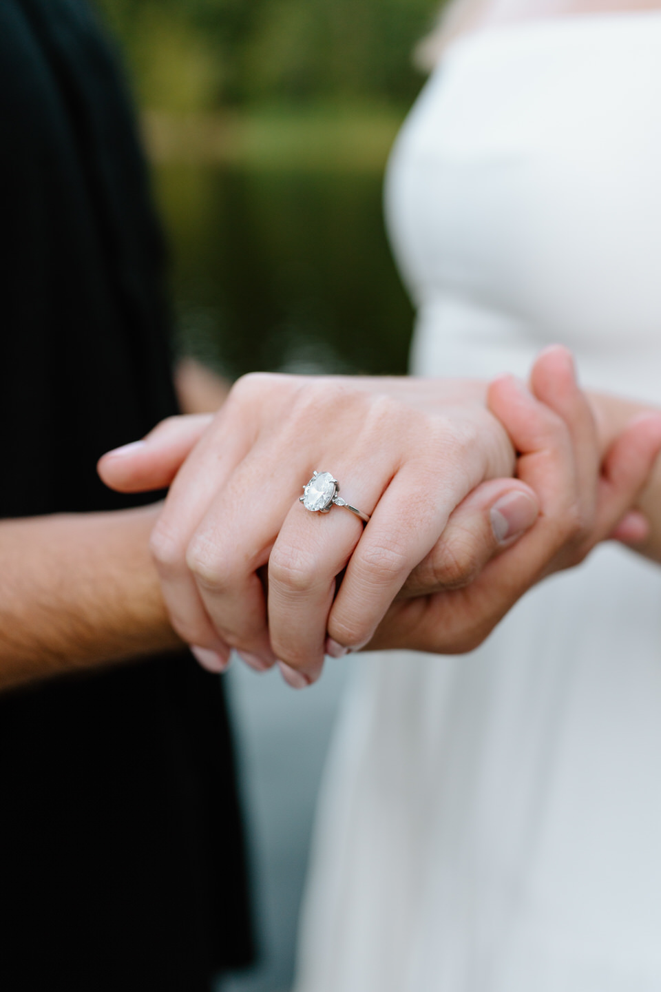Close-up of hands showing an engagement ring as the couple holds hands.