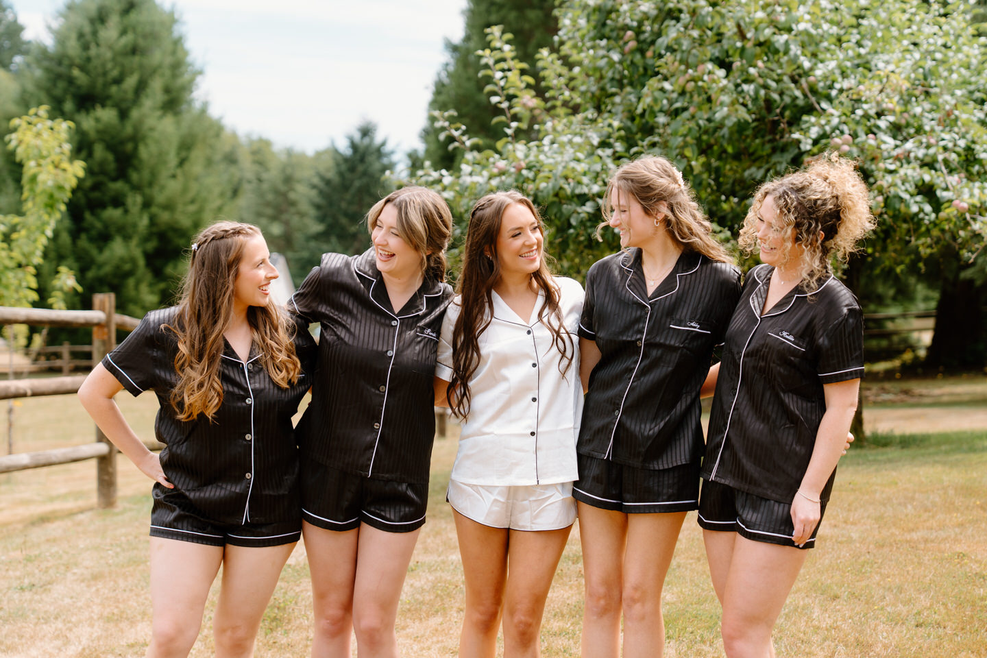 Hailey and her bridesmaids laughing together in matching black and white satin pajamas.
