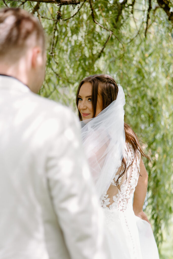 Bride looks over her shoulder during first look at Castle Rock Lavender Farm wedding.