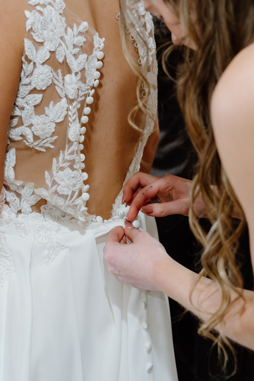 Sister of the bride helps button her wedding dress in the bridal suite at Castle Rock Lavender Farm.