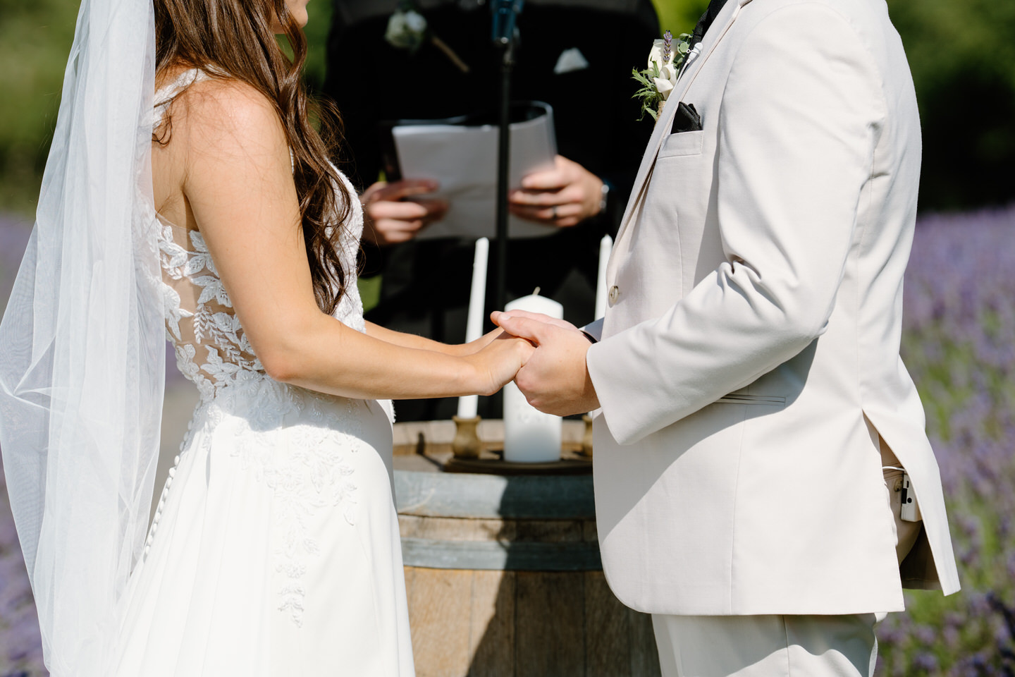 Close up of the bride and groom holding hands during their wedding ceremony.