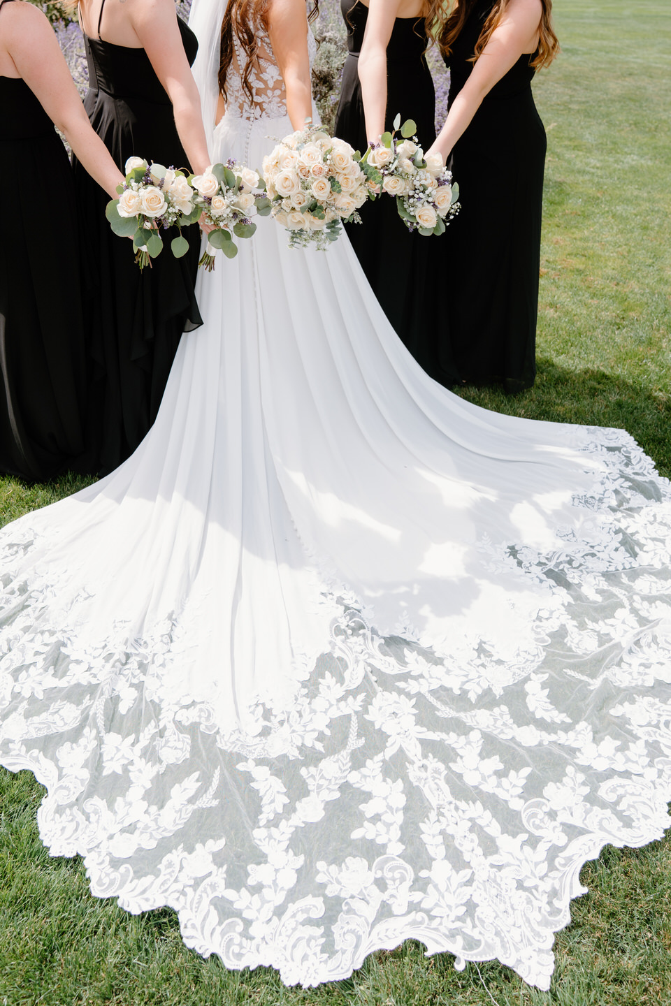Bride's lace train fanned out on the grass.