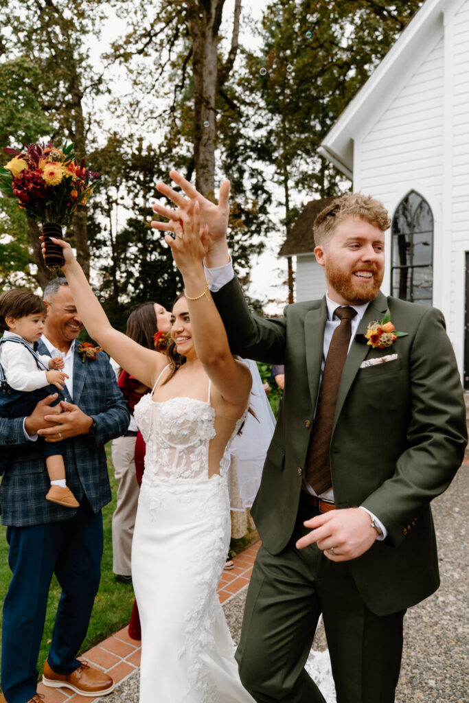 Newlyweds cheering with guests outside the chapel moments after their joyful Oaks Pioneer Church wedding ceremony.