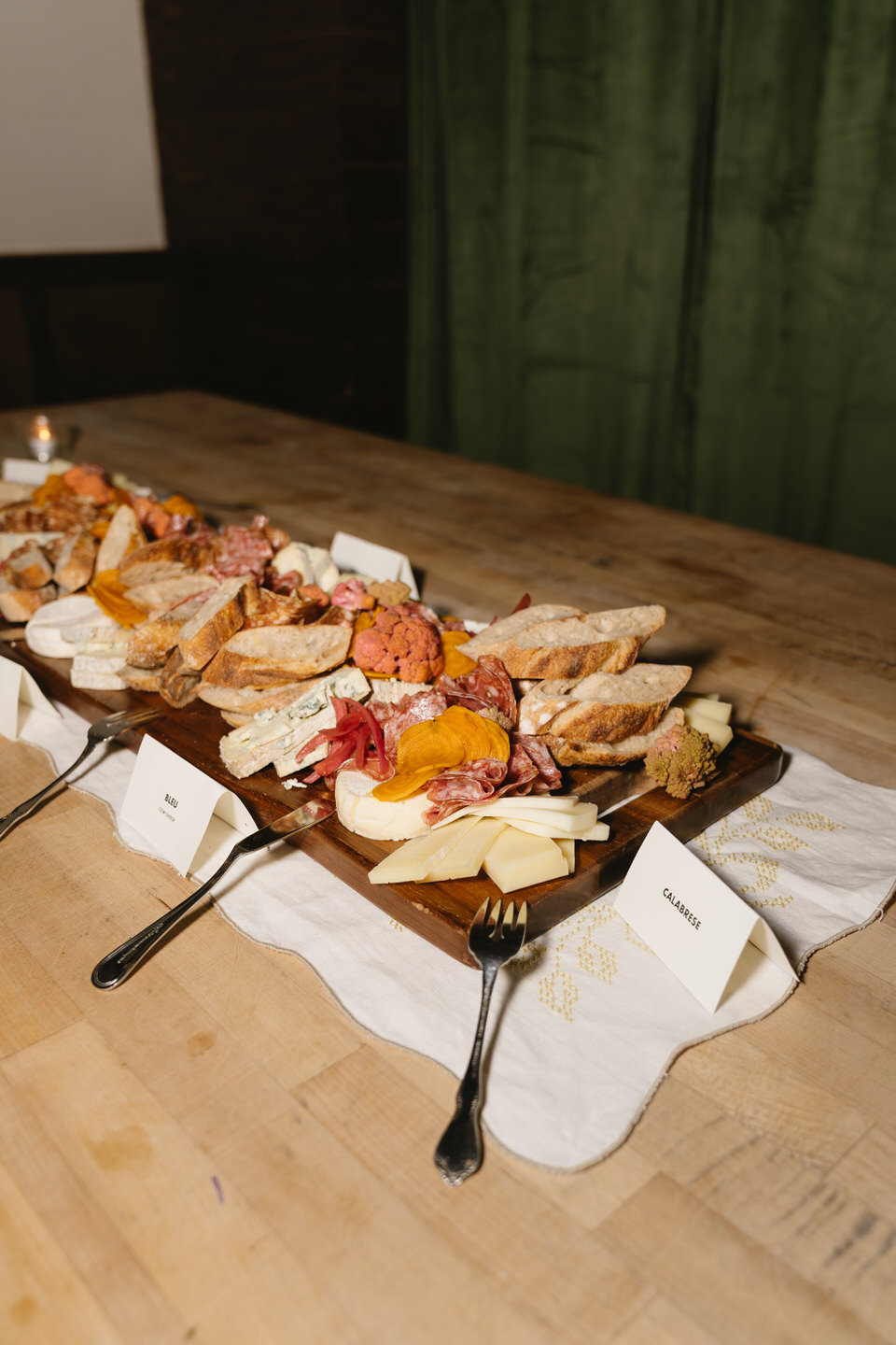 Charcuterie boards with cheeses and fruit arranged on a wooden table during a cozy reception at Café Olli after a Portland Oregon wedding.