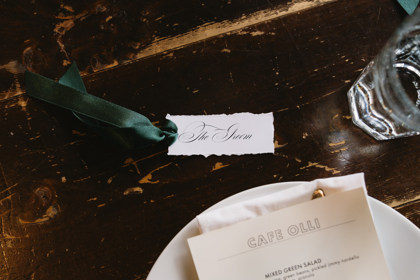 Close-up of wedding place card and menu on a candlelit table during the reception at Café Olli after an Oaks Pioneer Church wedding.