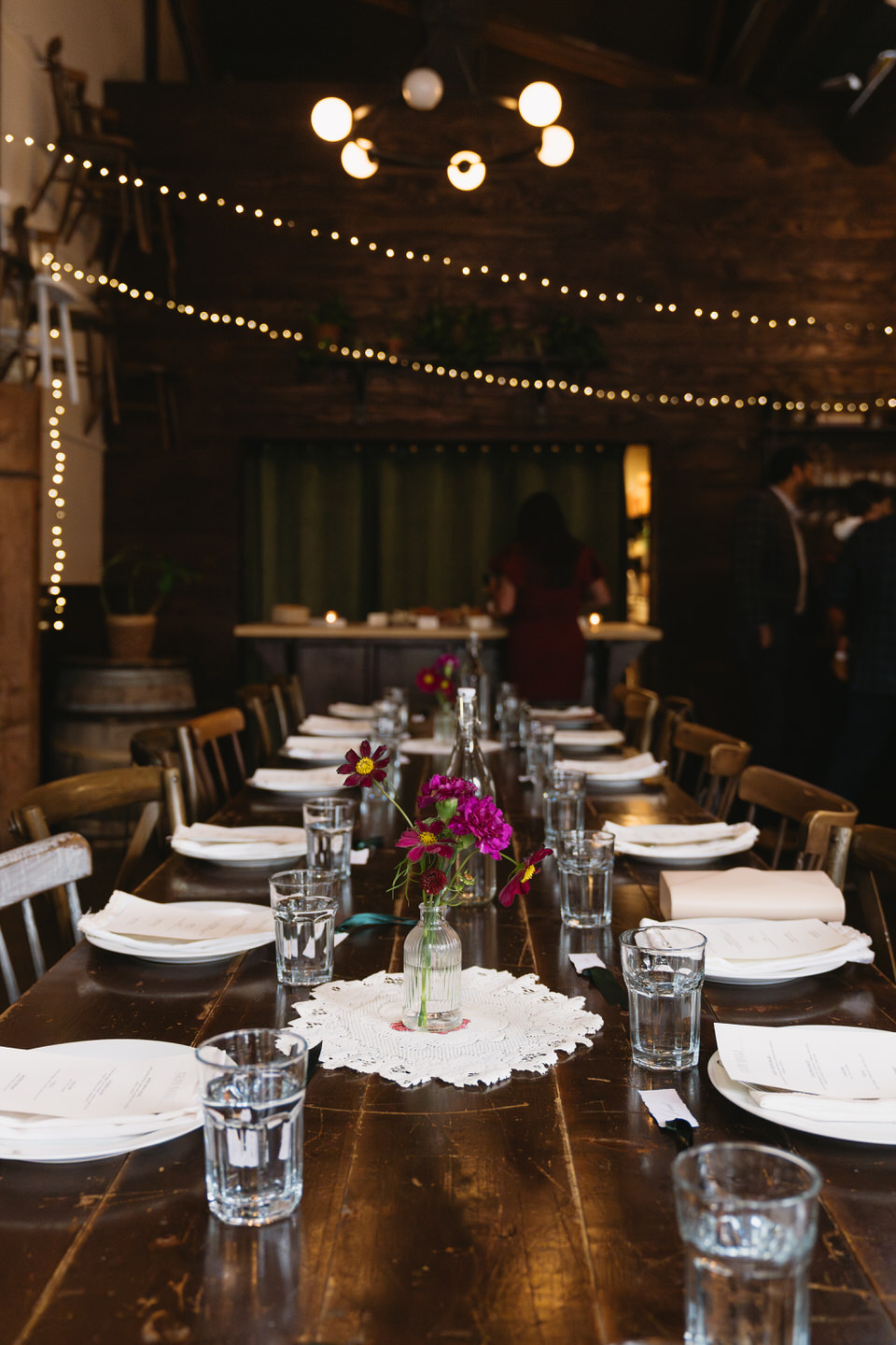 Long reception table with floral centerpieces and string lights at a cozy intimate wedding venue in Portland.