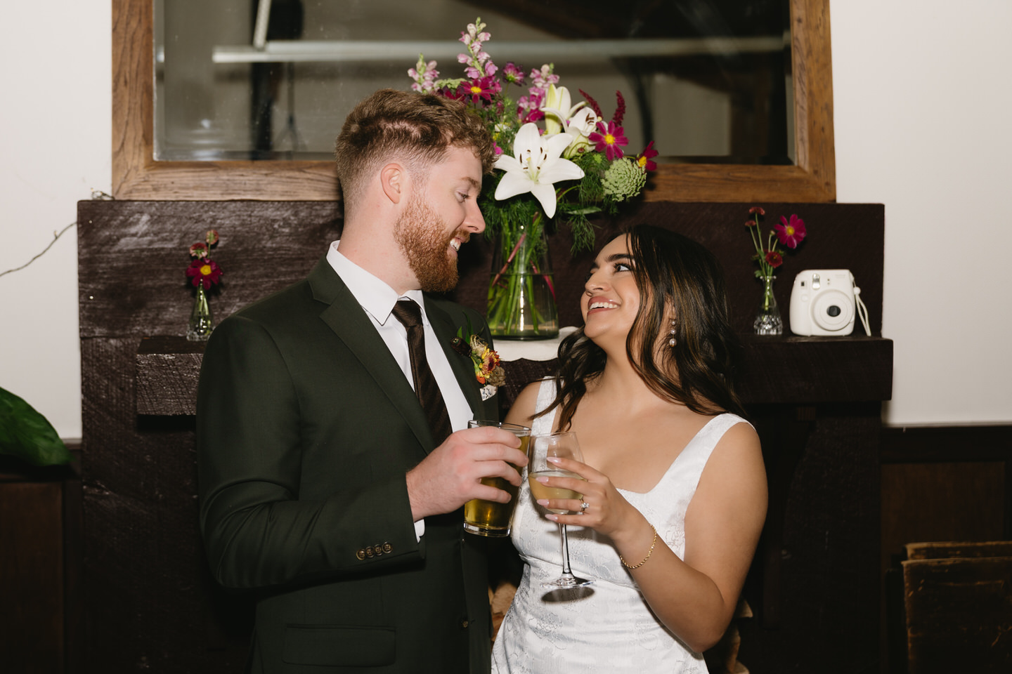 Bride and groom laughing together with drinks during celebration at their Cafe Olli wedding reception.