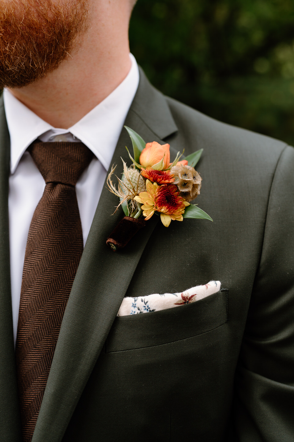 Groom boutonniere detail with fall flowers and brown tie during an elegant fall Portland wedding.