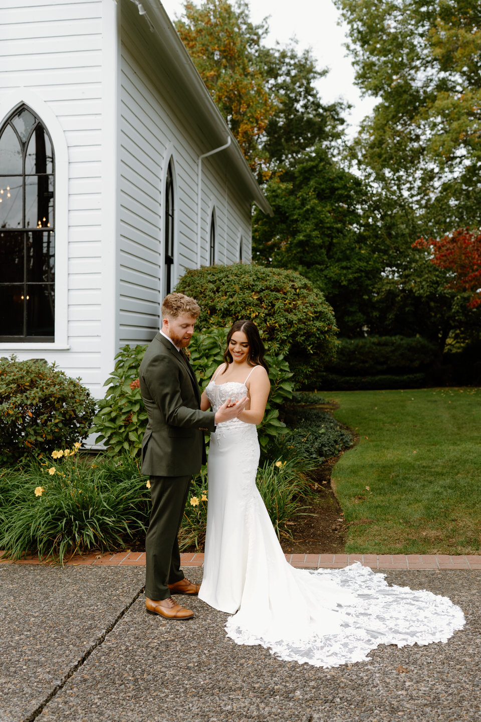Groom gently holding bride’s hands during portraits outside the chapel at their romantic Portland Oregon wedding.