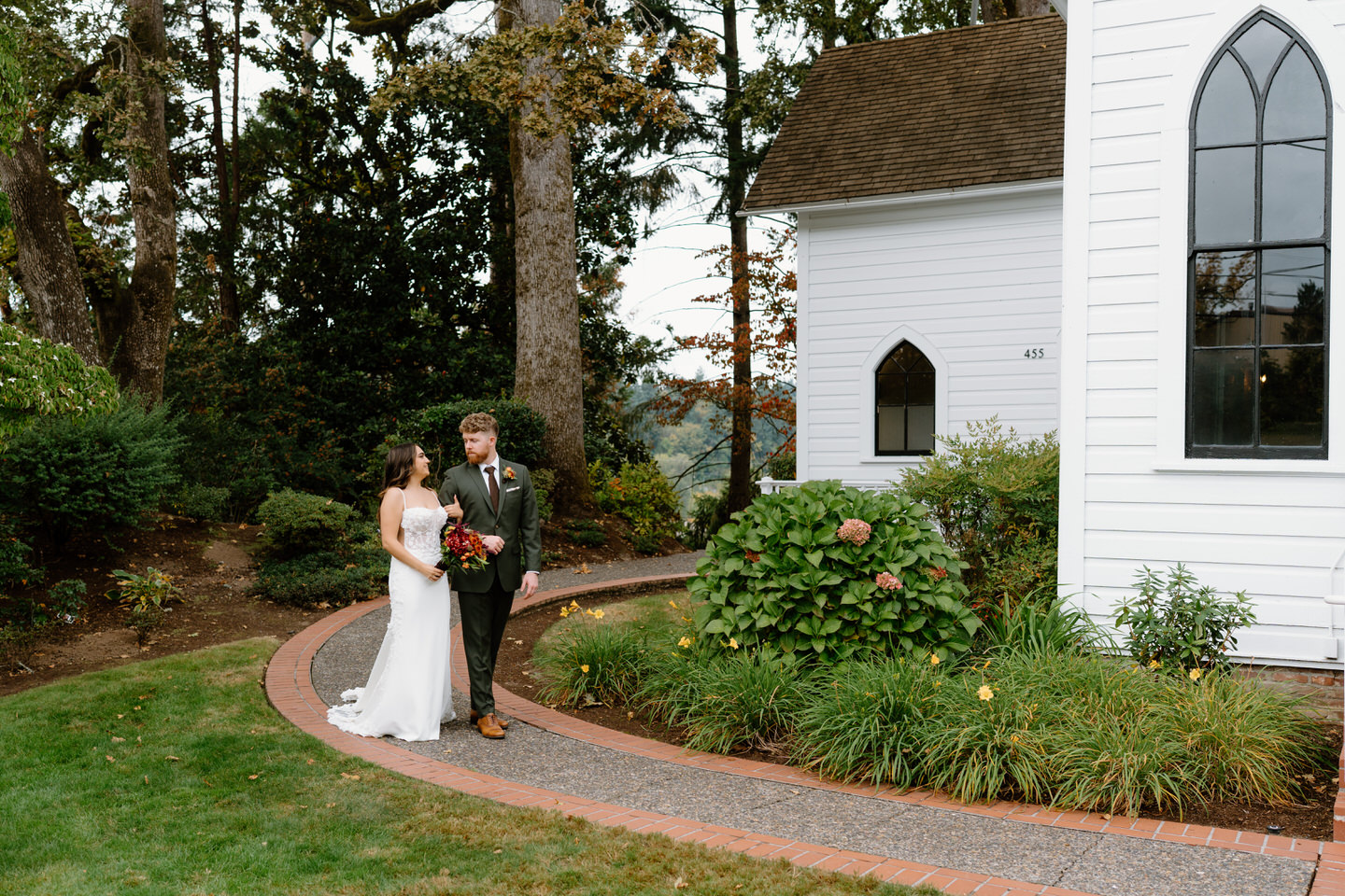 Couple standing together along the curved pathway near the chapel during a romantic fall Portland wedding portrait.