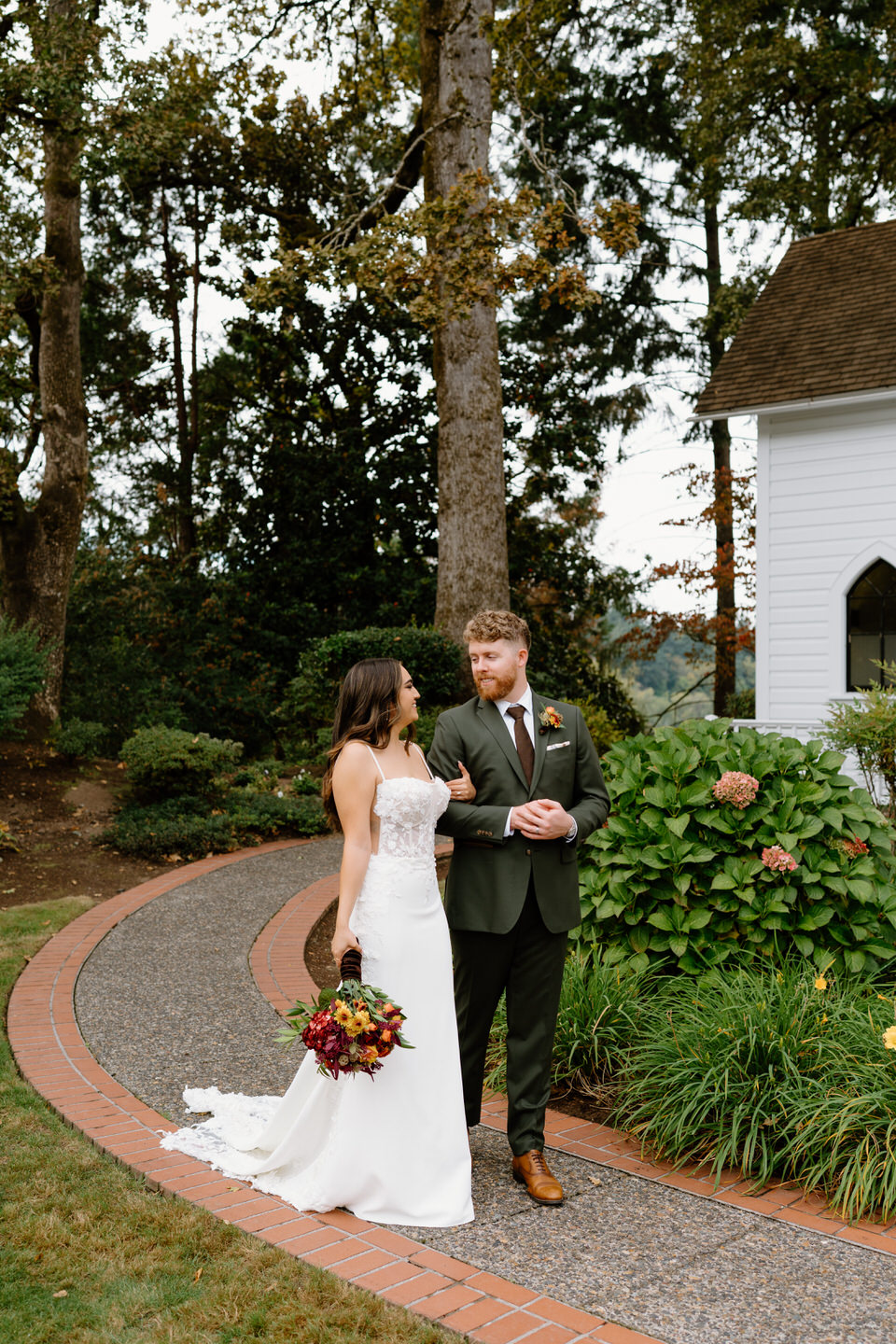 Bride and groom walk outside their wedding chapel in Portland, Oregon with a fall themed bouquet.