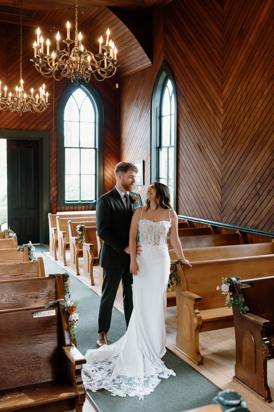 Newly married couple standing in the aisle inside the warm wood interior during their Oaks Pioneer Church wedding day.