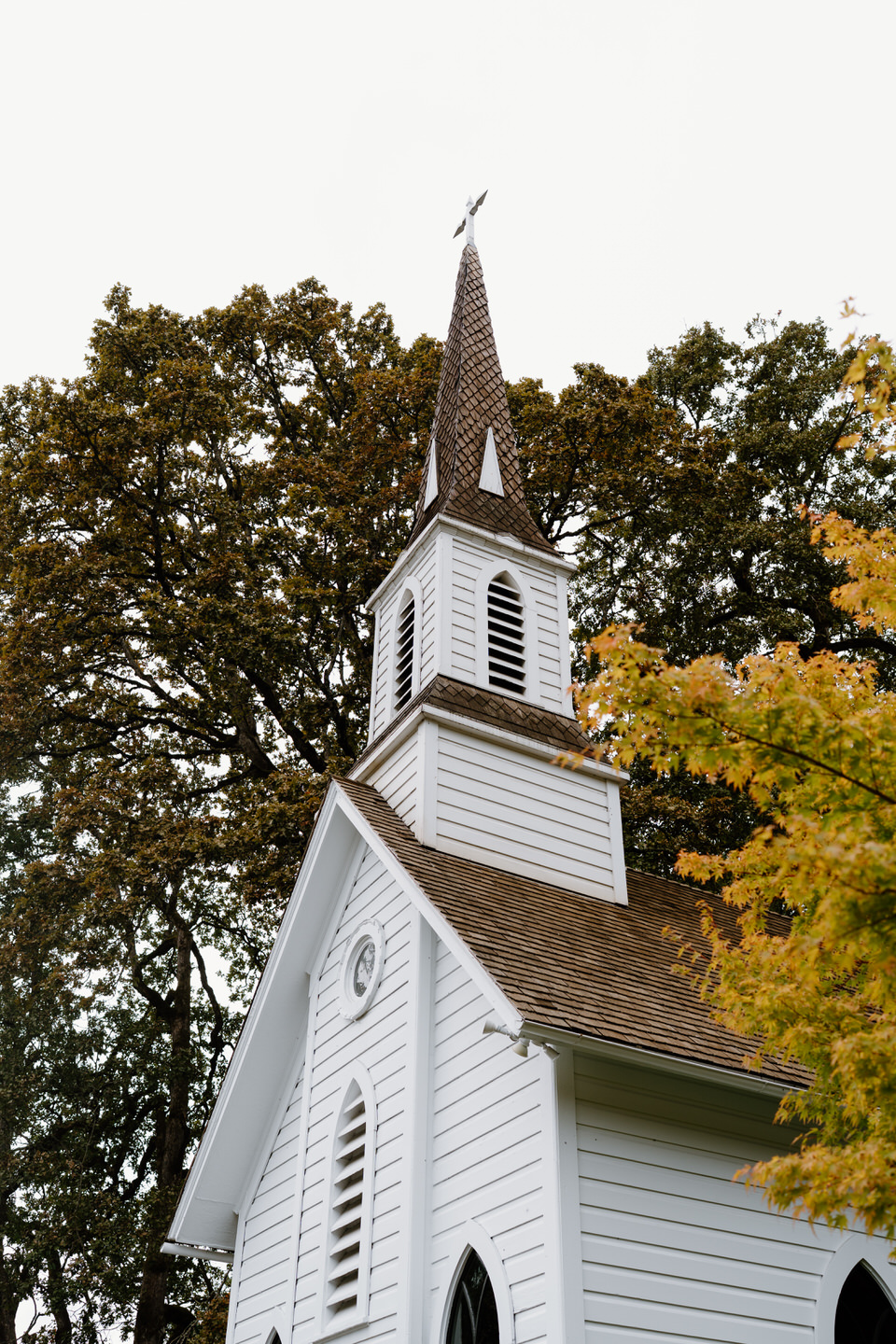 White historic church exterior surrounded by fall foliage at a charming Oaks Pioneer Church wedding venue in Portland.