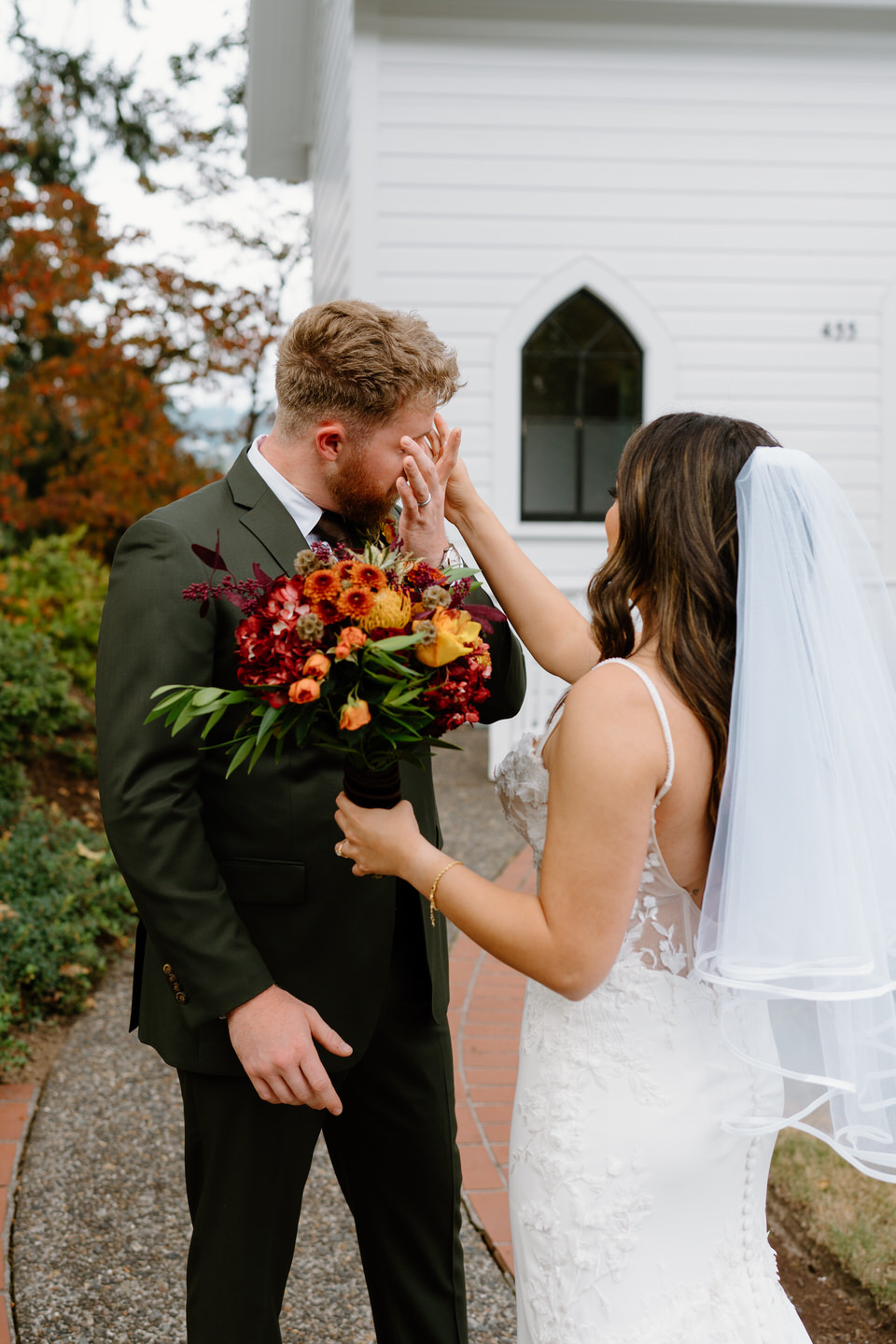 Groom wiping a happy tear while bride smiles during emotional portraits at their Oaks Pioneer Church wedding.
