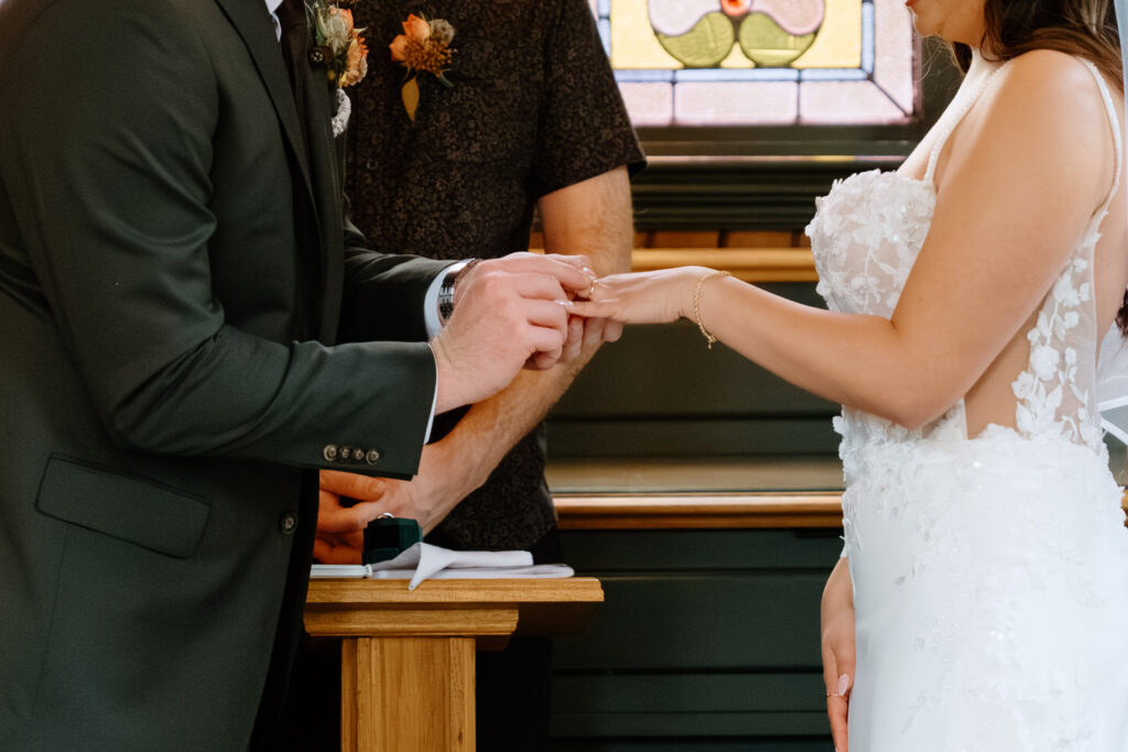 Close-up of bride and groom exchanging rings during a heartfelt Oaks Pioneer Church wedding ceremony in Portland, Oregon.
