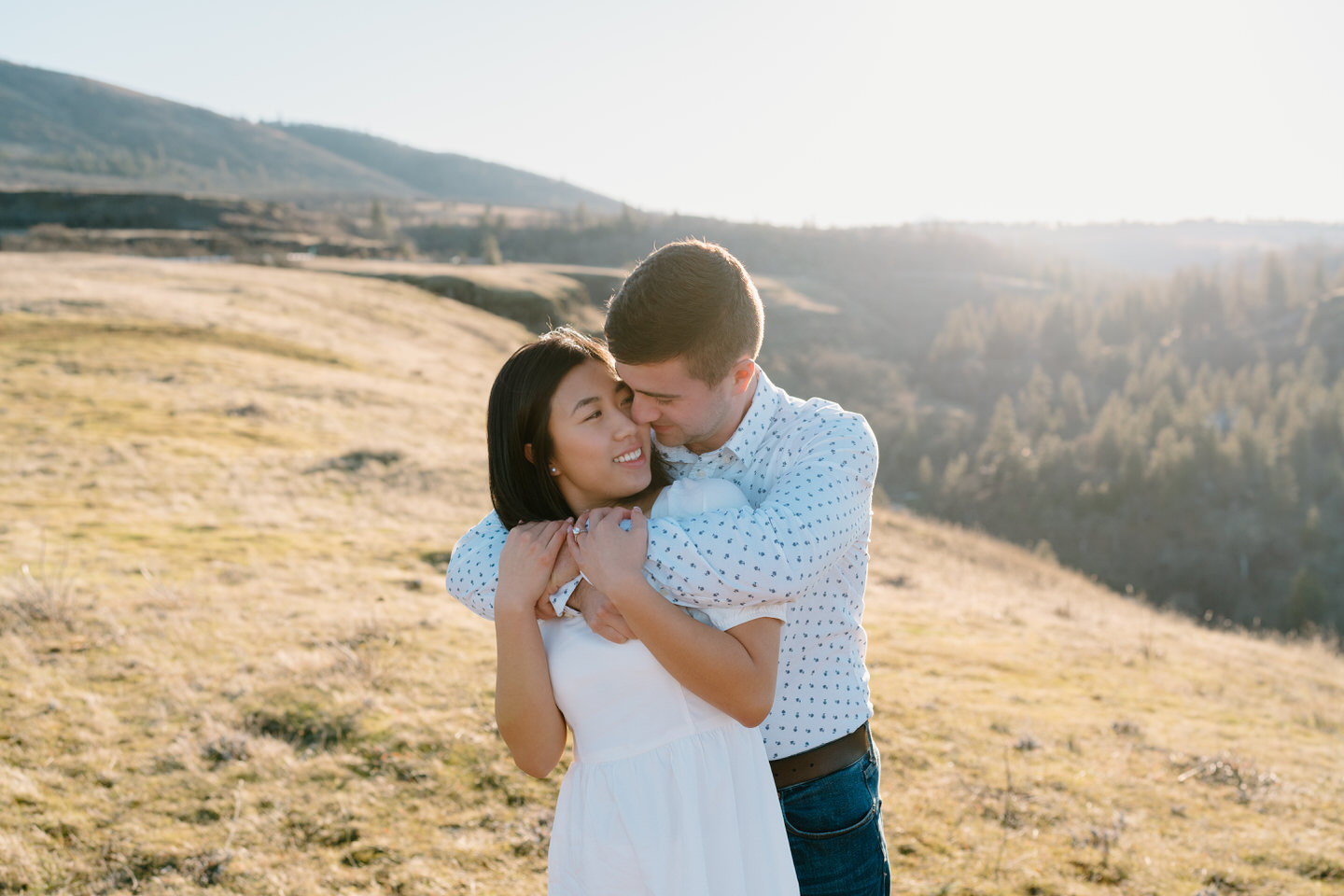 Alex wraps his arms around Min and smiles into the side of her head during Rowena Crest engagement photos.
