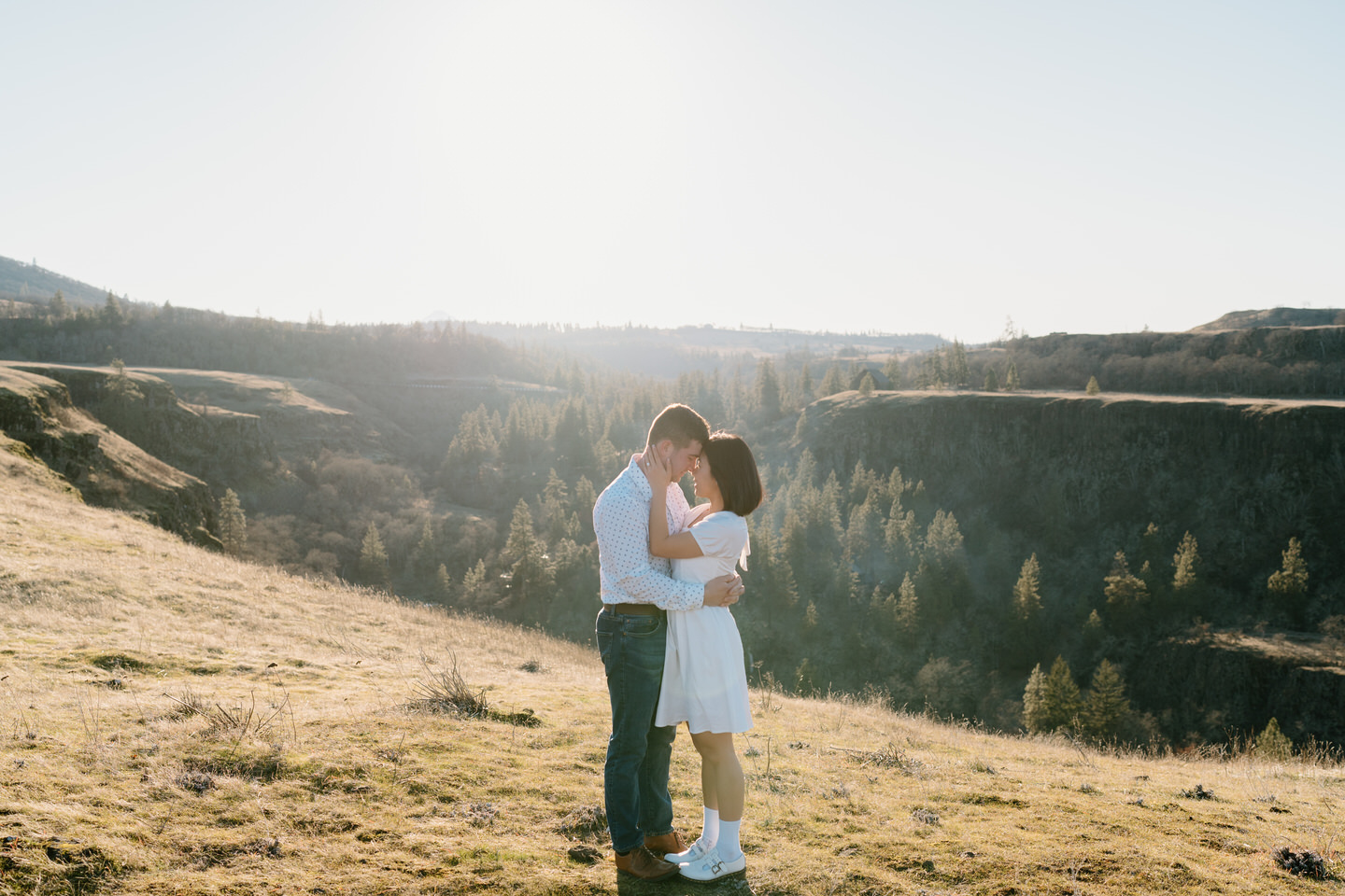 Alex and Min touch foreheads together in front of the Rowena Crest plateau cliffs.