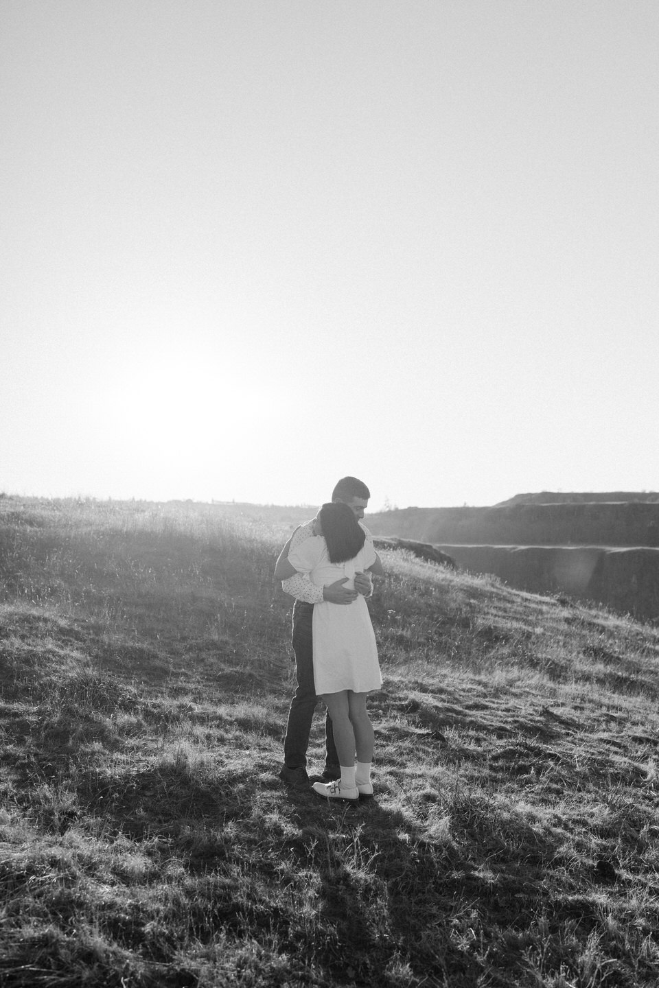 Alex and Min embrace on the hillside of Rowena Crest during their engagement photoshoot.