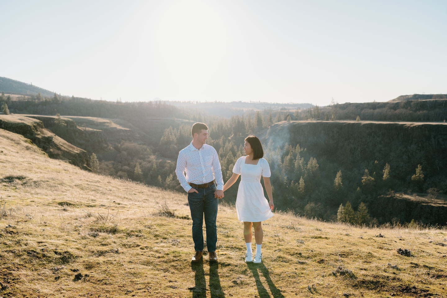 Alex and Min hold hands, standing a few steps apart for an editoral engagement photo.