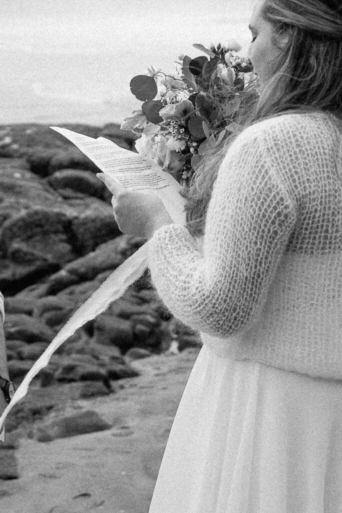 black and white detail photo of bride reading vows on oregon coast