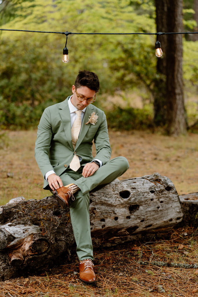 groom in sage green suit getting ready for wedding ceremony