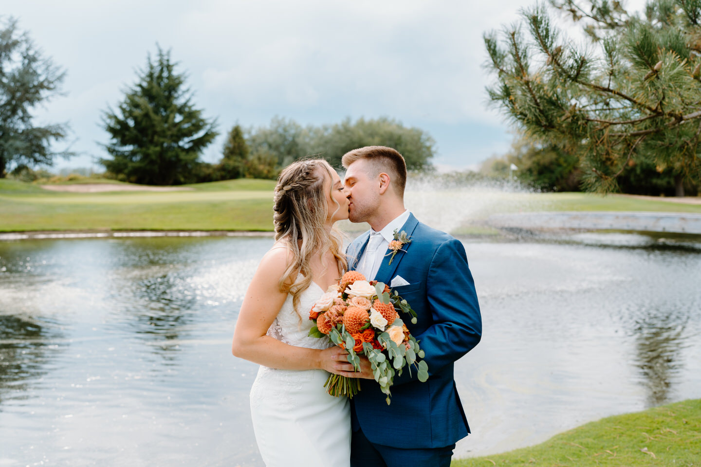Bride and groom kissing in front of water feature at shadow hills country club